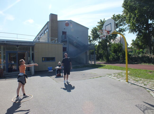 Eine Schülerin wirft einen Ball in Richtung Basketballkorb