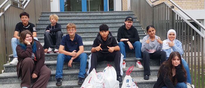 Schüler sitzen mit vollen Müllsäcken auf einer Treppe